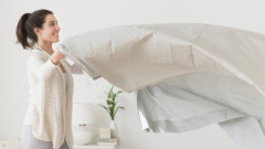 USA, New Jersey, Jersey City, Woman spreading sheet on bed